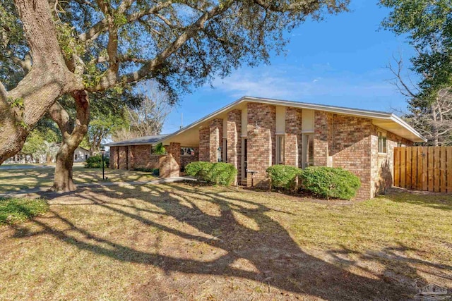 view of property exterior with a yard, brick siding, and fence