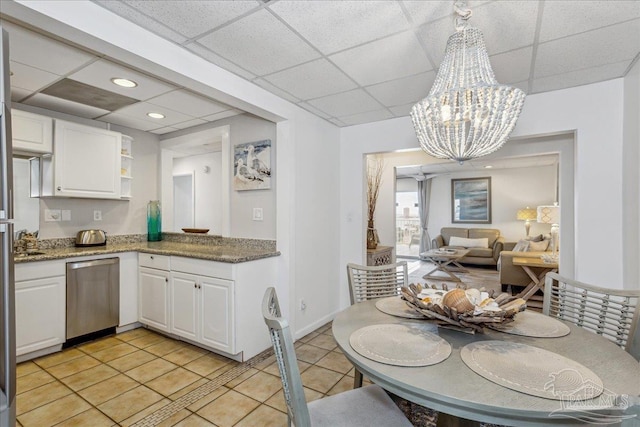 kitchen featuring stainless steel dishwasher, white cabinets, hanging light fixtures, and a notable chandelier