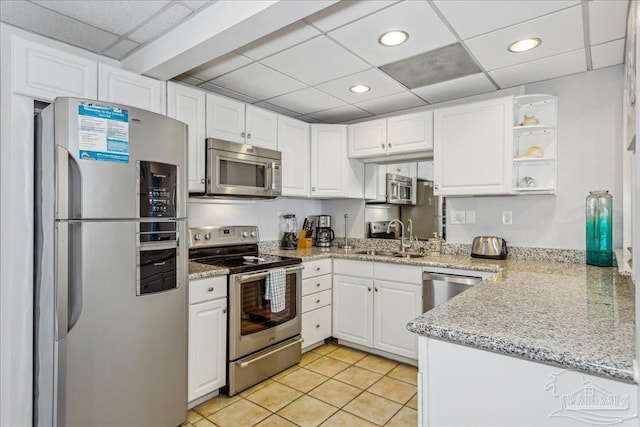 kitchen featuring white cabinetry, stainless steel appliances, light tile patterned flooring, a drop ceiling, and sink