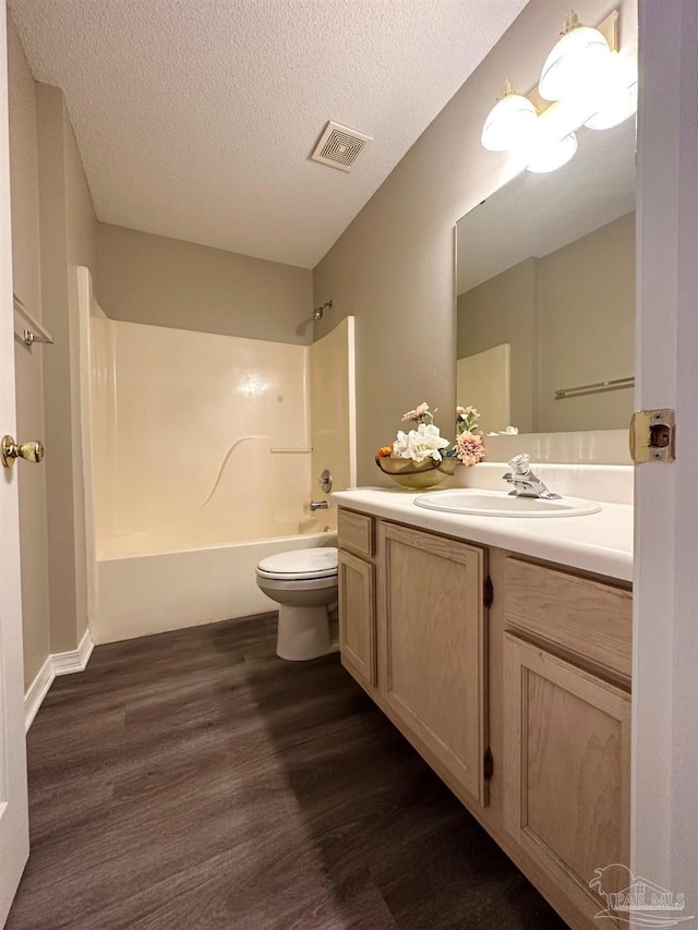 full bathroom featuring toilet, tub / shower combination, a textured ceiling, vanity, and hardwood / wood-style floors