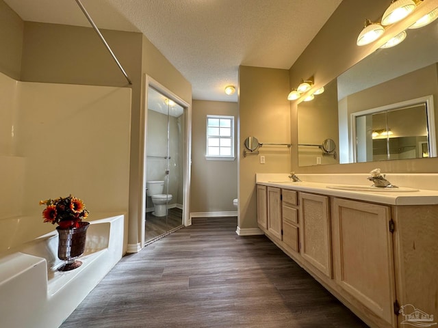 bathroom with toilet, a textured ceiling, vanity, a bathing tub, and hardwood / wood-style flooring