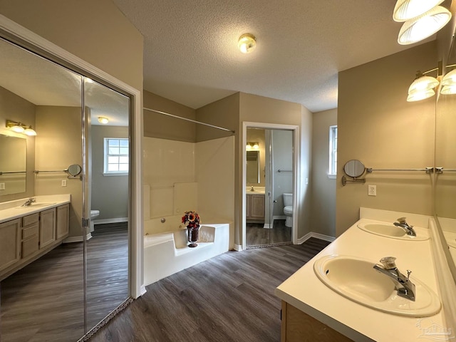 full bathroom featuring toilet, hardwood / wood-style floors, and a textured ceiling