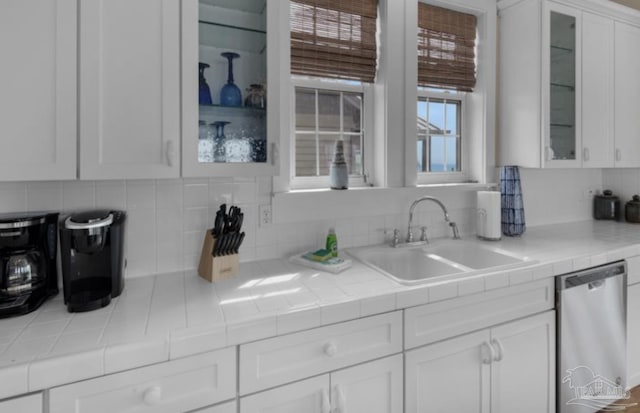 kitchen featuring dishwasher, backsplash, sink, tile counters, and white cabinetry