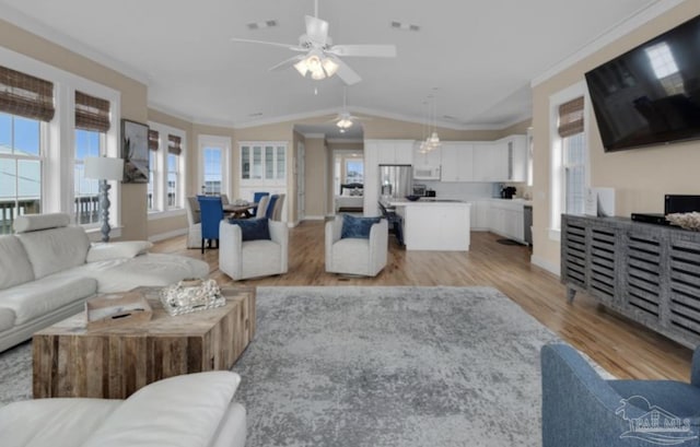 living room with lofted ceiling, light hardwood / wood-style flooring, ceiling fan, and ornamental molding