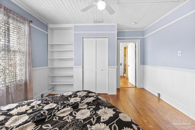 bedroom with hardwood / wood-style floors, ornamental molding, ceiling fan, a closet, and wooden ceiling