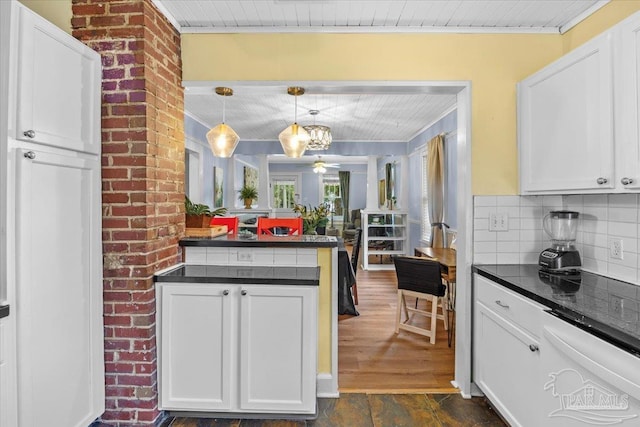 kitchen with pendant lighting, a notable chandelier, white cabinetry, backsplash, and dark wood-type flooring