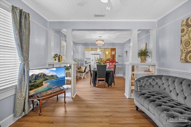 living room featuring ornamental molding, ceiling fan with notable chandelier, decorative columns, and light hardwood / wood-style floors