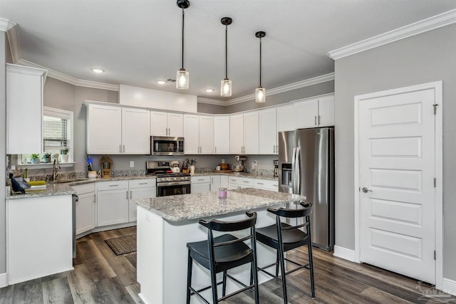 kitchen with white cabinets, appliances with stainless steel finishes, a center island, and pendant lighting