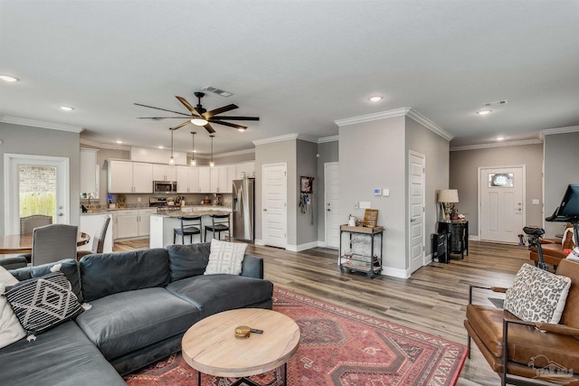 living room featuring hardwood / wood-style flooring, ceiling fan, and crown molding