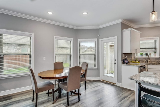 dining area with a healthy amount of sunlight, wood-type flooring, and crown molding