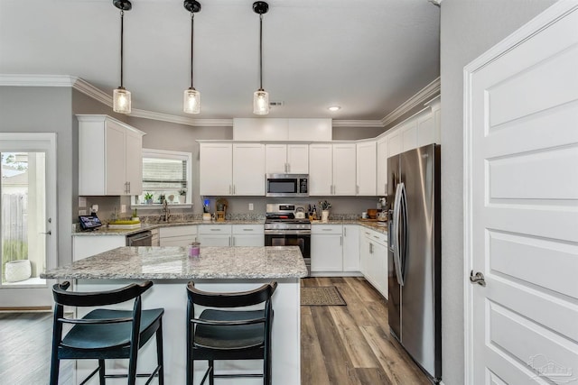 kitchen featuring white cabinets, appliances with stainless steel finishes, a center island, and hardwood / wood-style floors