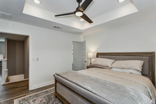 bedroom featuring a tray ceiling, ceiling fan, and dark hardwood / wood-style floors