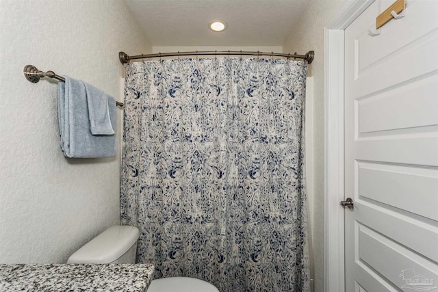 bathroom featuring curtained shower, toilet, and a textured ceiling