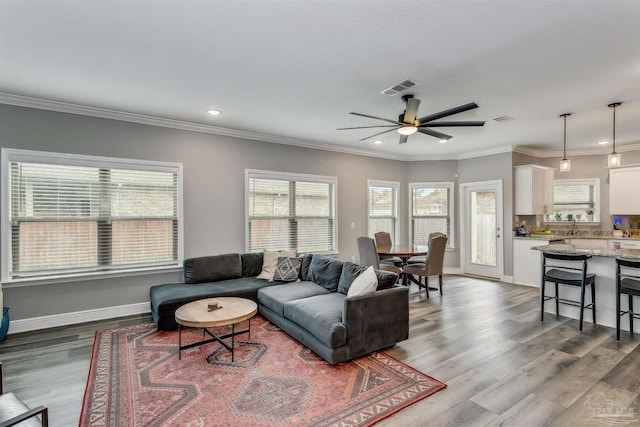 living room with hardwood / wood-style flooring, ceiling fan, and ornamental molding