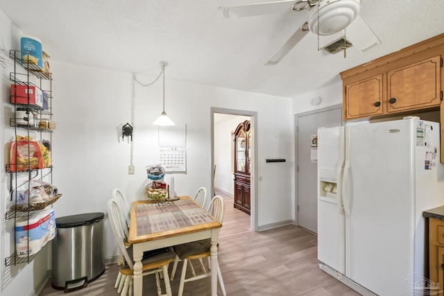 kitchen featuring a textured ceiling, ceiling fan, decorative light fixtures, light hardwood / wood-style floors, and white fridge with ice dispenser