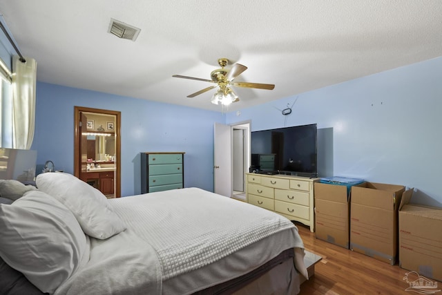 bedroom featuring ceiling fan, dark hardwood / wood-style flooring, a textured ceiling, and ensuite bath