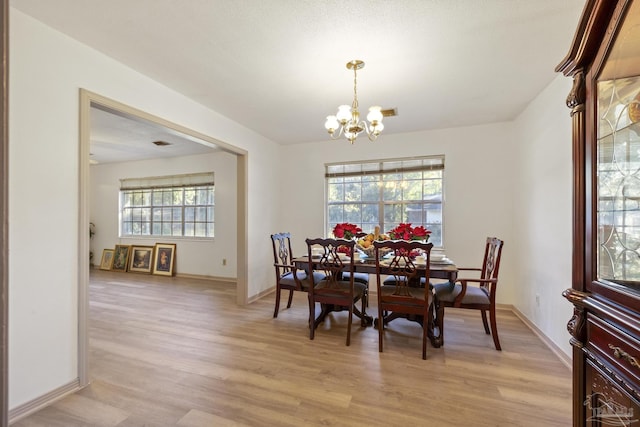 dining room featuring light wood-type flooring, an inviting chandelier, and a wealth of natural light