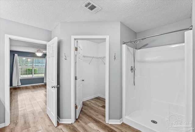 bathroom featuring hardwood / wood-style flooring, a textured ceiling, and a shower