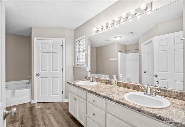 bathroom featuring a washtub, vanity, wood-type flooring, and a textured ceiling