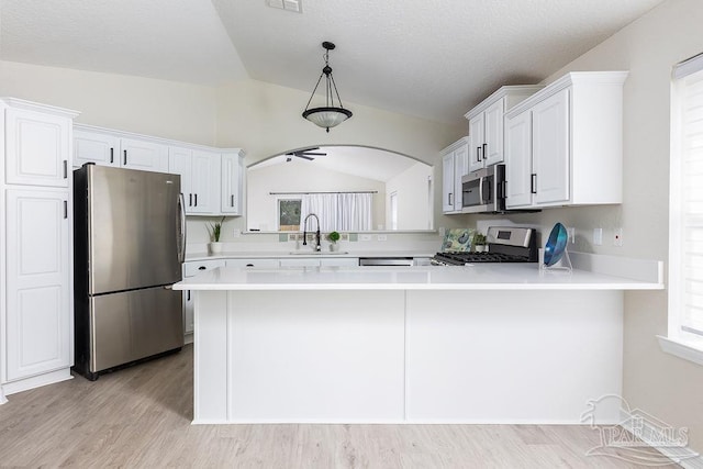 kitchen with appliances with stainless steel finishes, kitchen peninsula, sink, and white cabinets