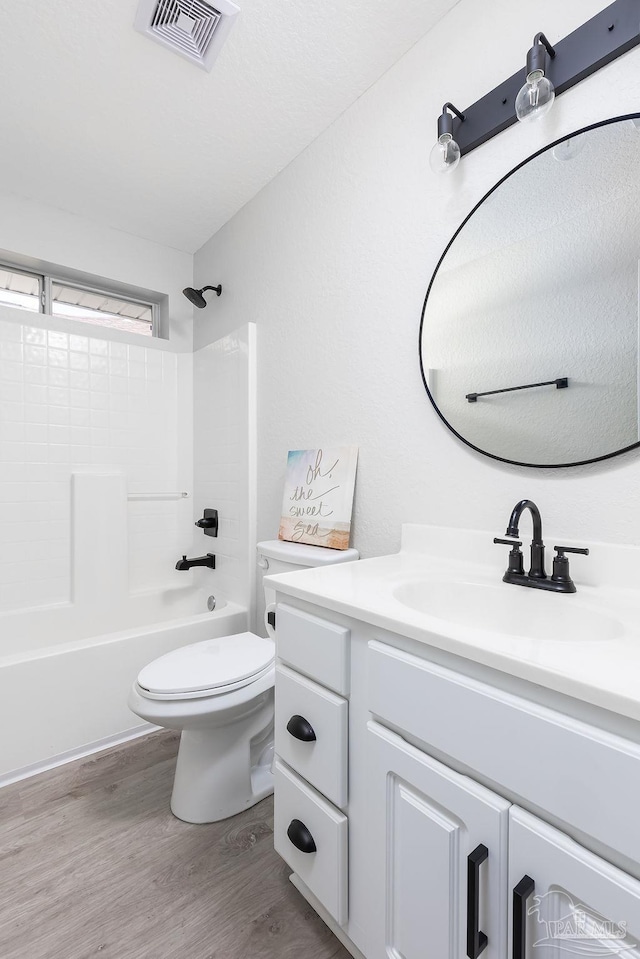 full bathroom featuring hardwood / wood-style flooring, vanity, washtub / shower combination, and toilet