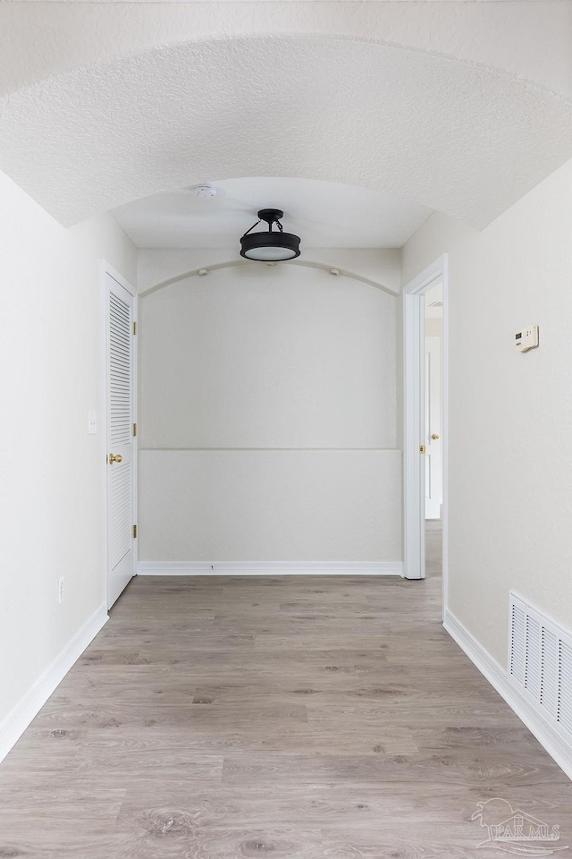 spare room featuring wood-type flooring and a textured ceiling