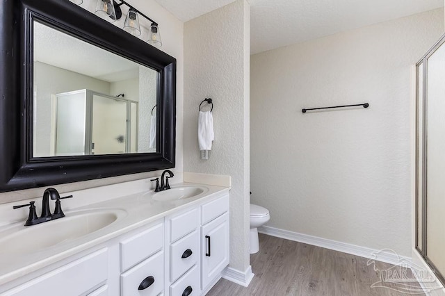 bathroom with vanity, hardwood / wood-style floors, toilet, and an enclosed shower