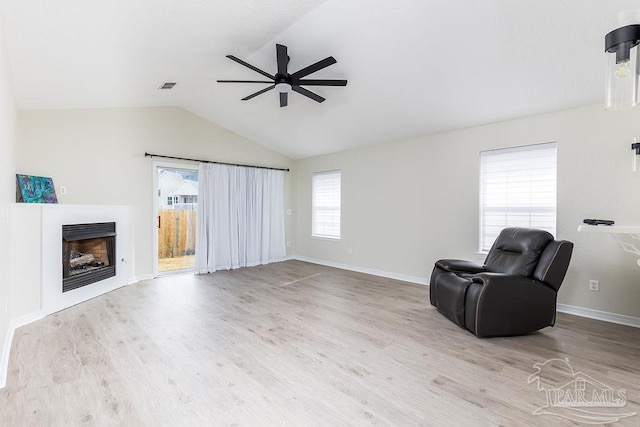 living area featuring ceiling fan, lofted ceiling, and light wood-type flooring