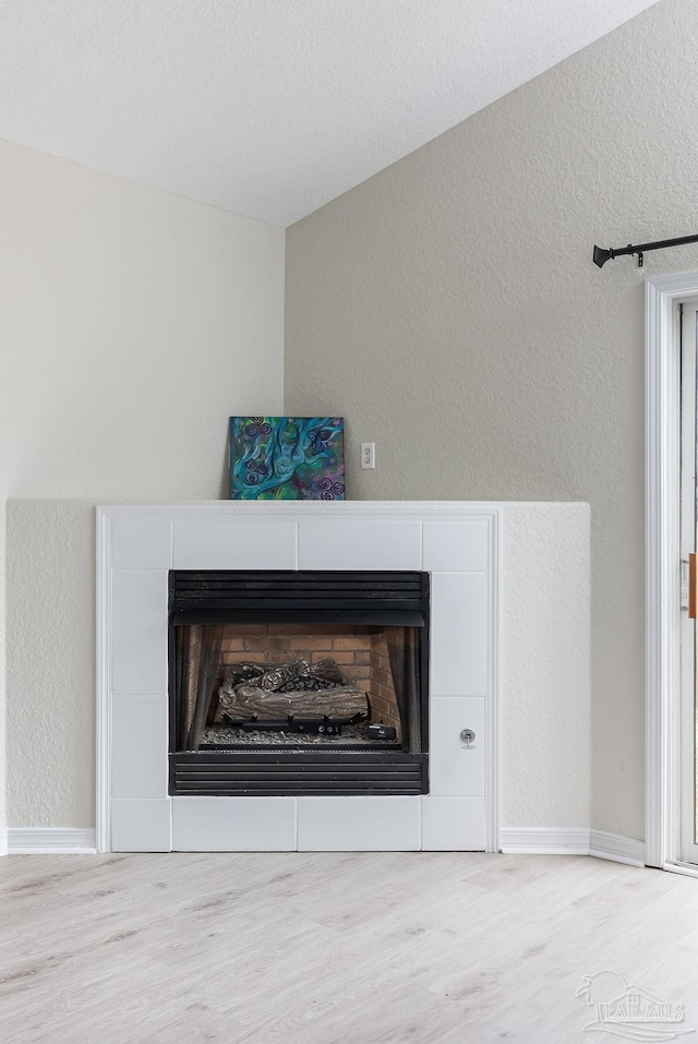 room details with hardwood / wood-style floors and a tile fireplace