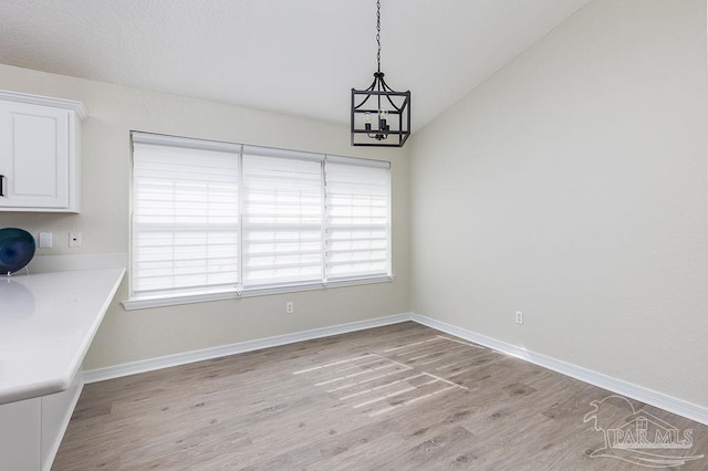 unfurnished dining area with a notable chandelier and light hardwood / wood-style flooring