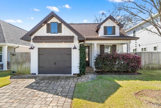 view of front facade with a front yard, decorative driveway, fence, and an attached garage