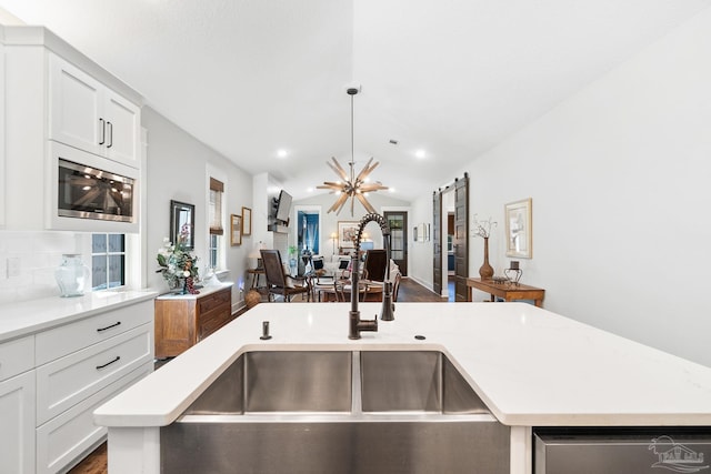 kitchen with stainless steel microwave, decorative backsplash, light countertops, and vaulted ceiling