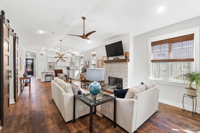 living area featuring a wealth of natural light, a barn door, lofted ceiling, and a fireplace