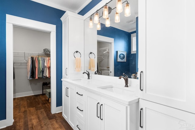 full bathroom with a sink, a walk in closet, wood finished floors, and double vanity