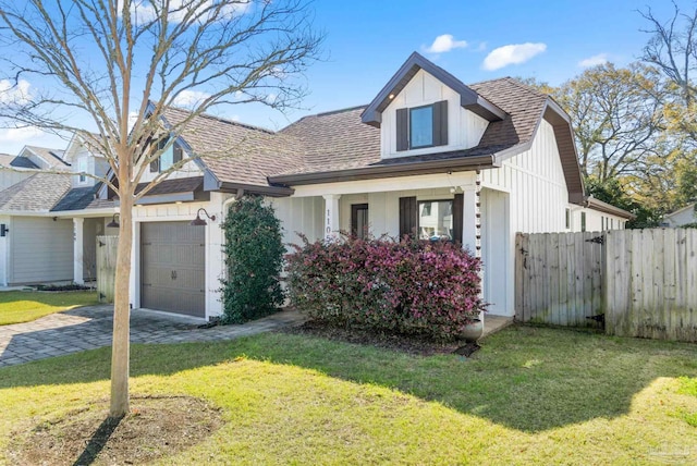 view of front of home with board and batten siding, a front lawn, fence, a garage, and driveway