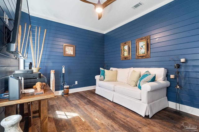 living area with wood finished floors, visible vents, and baseboards