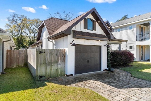 exterior space with a garage, roof with shingles, a front yard, and fence