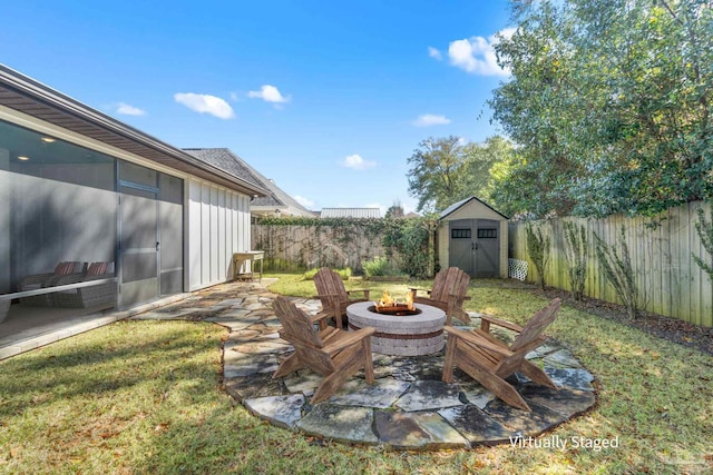 view of yard featuring a storage unit, an outbuilding, a fenced backyard, an outdoor fire pit, and a patio area