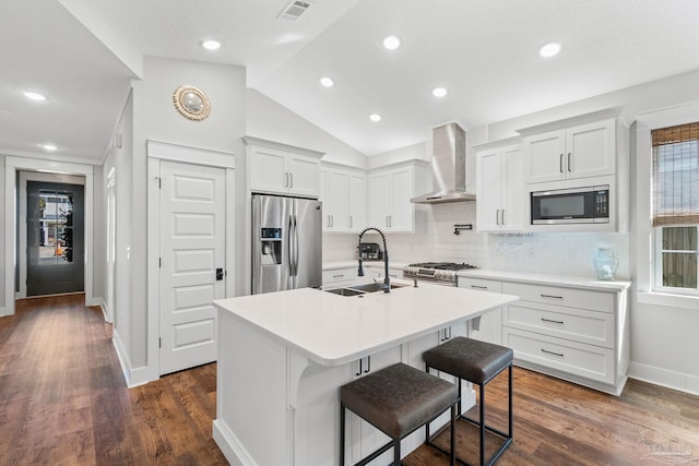 kitchen featuring a sink, appliances with stainless steel finishes, wall chimney exhaust hood, and dark wood-style flooring