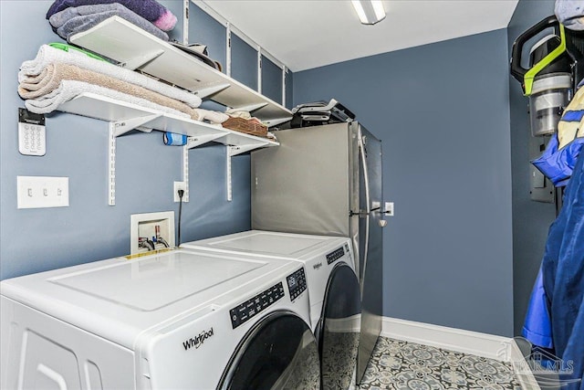 washroom featuring baseboards, tile patterned floors, washer and clothes dryer, and laundry area