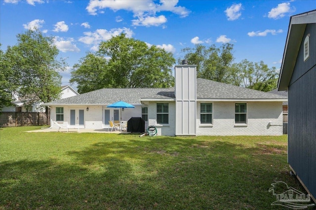 back of property with a chimney, a yard, a patio area, french doors, and brick siding
