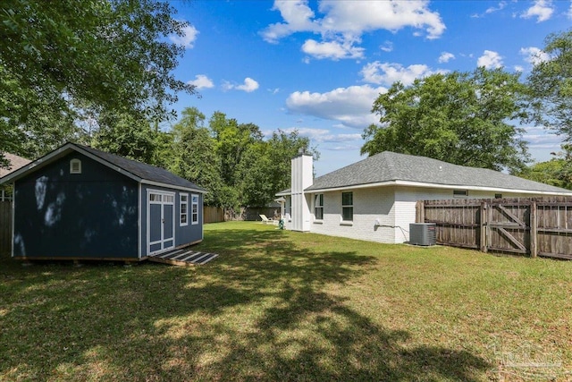 view of yard featuring a fenced backyard, an outbuilding, and central AC