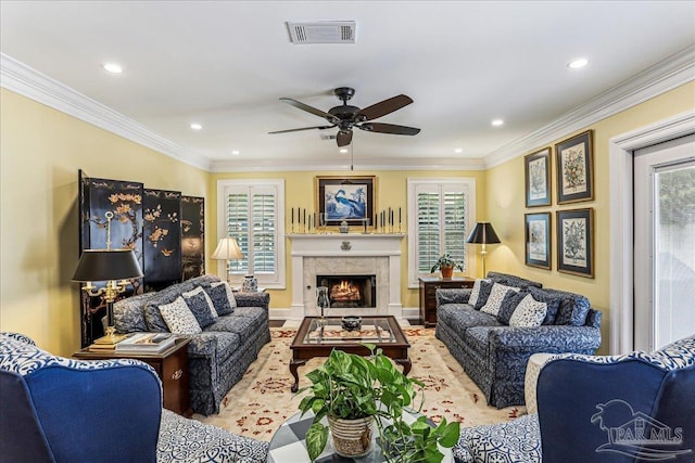 living room with ceiling fan, crown molding, visible vents, and a fireplace