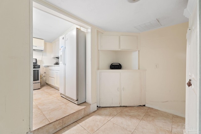 kitchen with white cabinetry, light tile patterned floors, stainless steel range oven, custom exhaust hood, and white fridge with ice dispenser