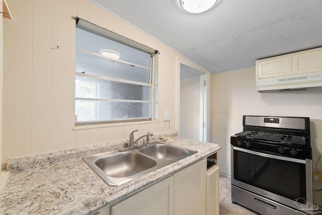 kitchen featuring a sink, light countertops, gas range, and under cabinet range hood