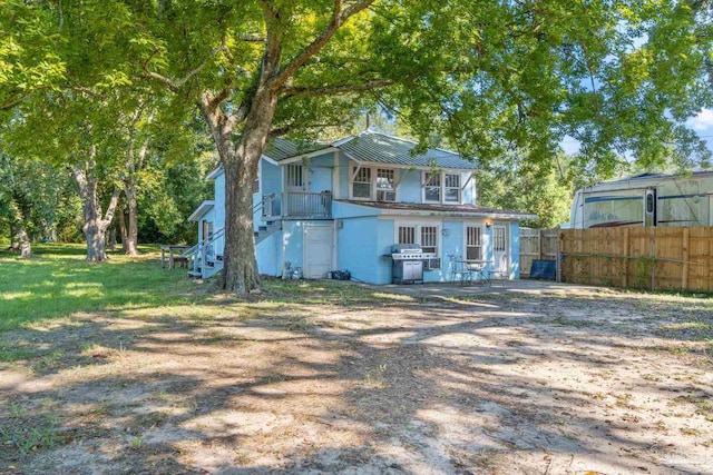 rear view of house featuring a yard, fence, and stairway