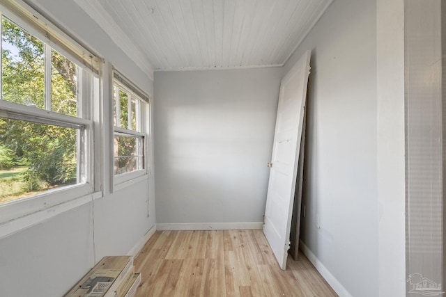 interior space featuring ornamental molding, light wood-style flooring, baseboards, and wood ceiling