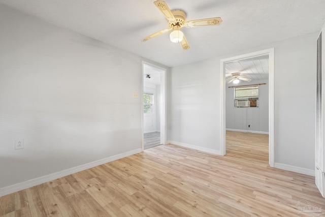 spare room with baseboards, light wood-type flooring, and a ceiling fan