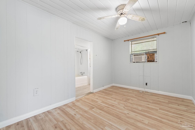 empty room featuring light wood-type flooring, ceiling fan, wooden walls, and cooling unit