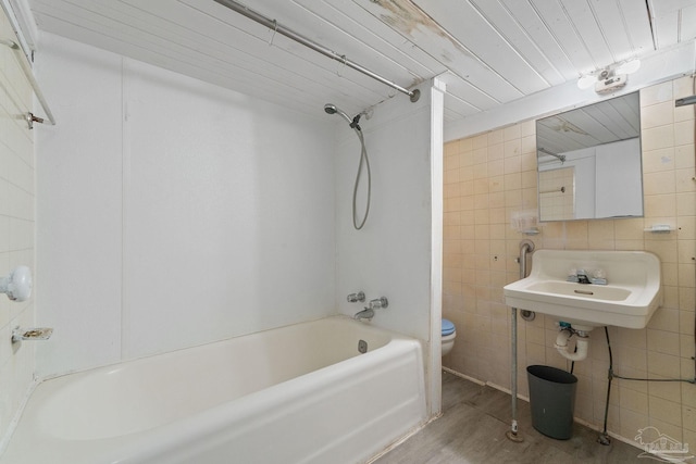 full bathroom with toilet, sink, tub / shower combination, tile walls, and hardwood / wood-style floors